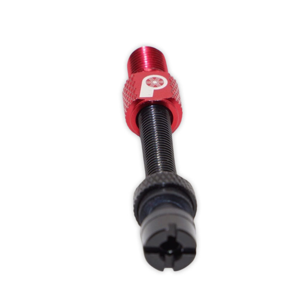 The Prestacycle Prestadapter TUBELESS—a Presta adapter and valve core remover—features a red lightweight alloy cap, black threaded body, and rubber gasket, shown in close-up on a white background.