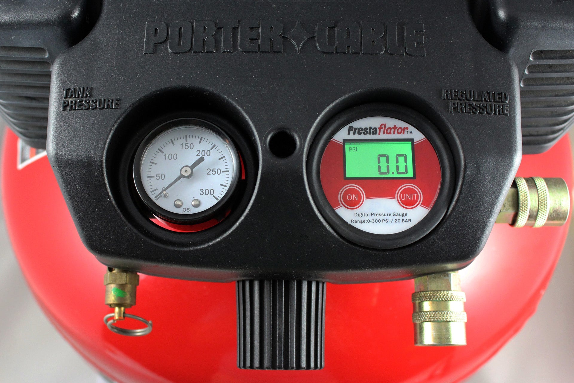Close-up of a Prestacycle Prestaflator Digital Gauge for Air Compressors &amp; Floor Pumps with an analog tank pressure gauge, both showing clear dials and connectors, set against a vivid red background.