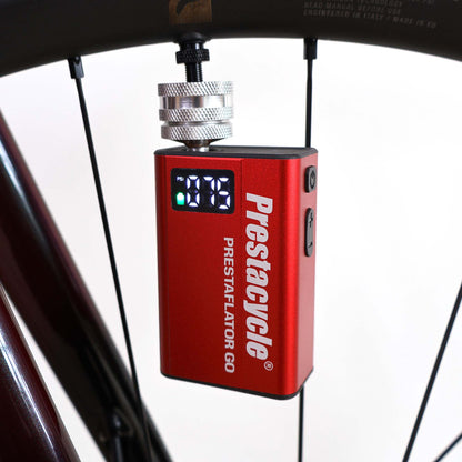 A red Prestacycle Prestaflator GO Portable Digital Rechargeable Preset Bicycle Tire Inflator, perfect for electric bikes, is connected to a bicycle wheel and shows the pressure reading on its display.