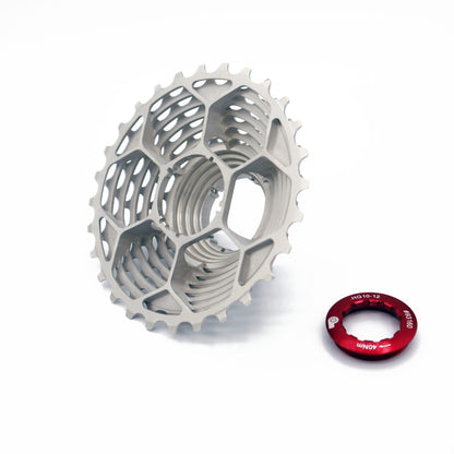 The Prestacycle UniBlock PRO 12 speed cassette by Prestacycle, made from tough ChroMoly steel with a honeycomb design, is shown beside a small red component. It’s Shimano HG12 compatible for smooth shifting on a white background.